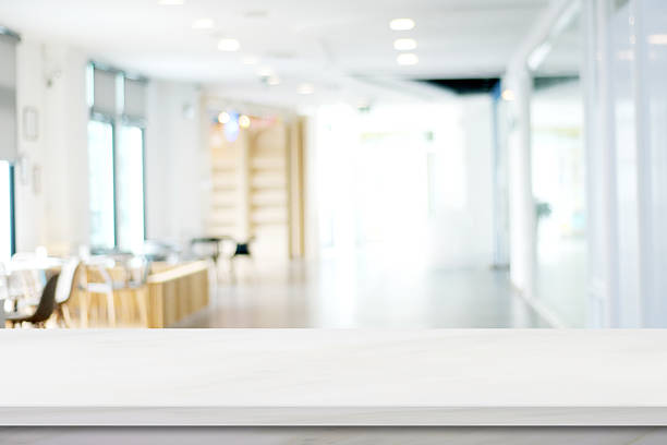 Empty wooden table with abstract blurred and illuminated office, lobby or home interior background