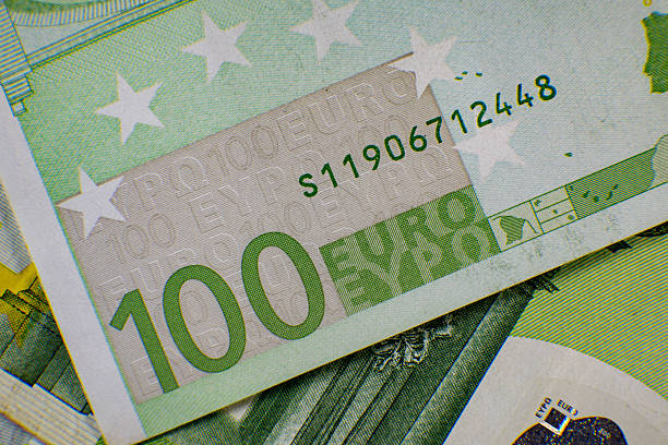 Detailed view of a 100 euro banknote focuses on its design, featuring the security elements and colors that make euro currency unique and recognizable.
