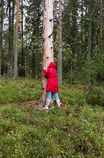 istock A middle-aged Caucasian woman in a red coat hugs a tree trunk. 2235594826