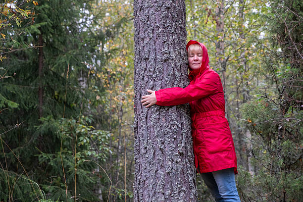 istock A middle-aged Caucasian woman in a red coat hugs a tree trunk. 2235595188