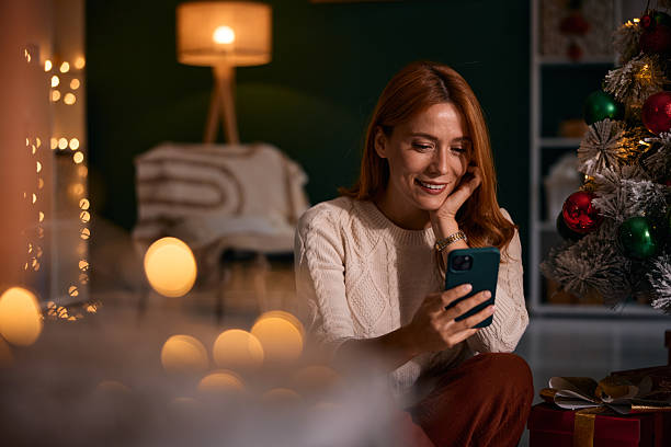 istock Woman using smartphone next to Christmas tree during holidays 2235595438