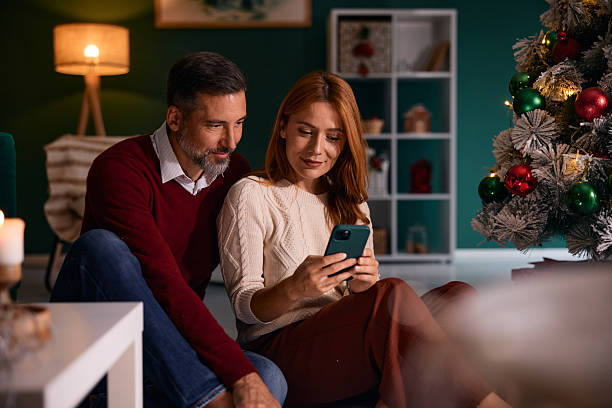 istock Couple using smartphone near Christmas tree at home 2235595998