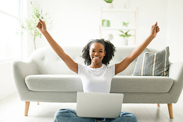 istock Young woman sitting on floor by the couch using laptop. Afemale working on laptop computer at home. 2235596886