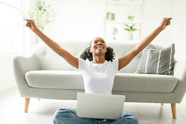 istock Young woman sitting on floor by the couch using laptop. Afemale working on laptop computer at home. 2235596888