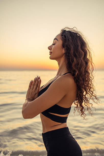 istock A serene woman practicing meditation by the ocean at sunset 2235597344