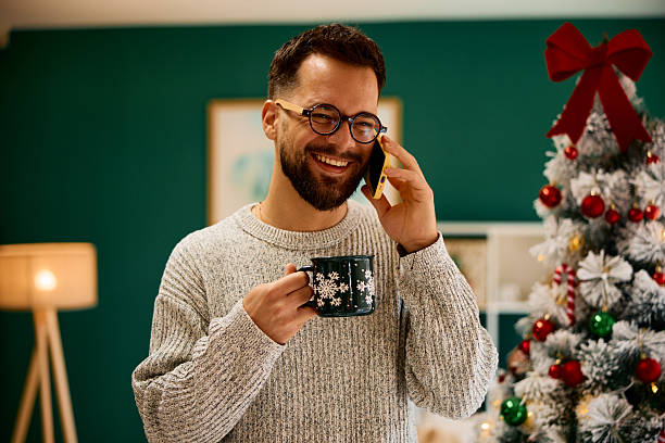 istock Young man talking on the phone and drinking coffee during Christmas holidays 2235598372