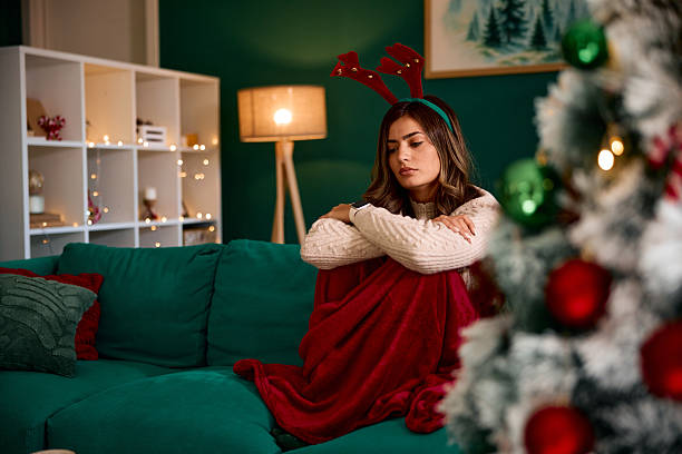 istock Sad woman sitting alone on sofa during Christmas holidays 2235598469