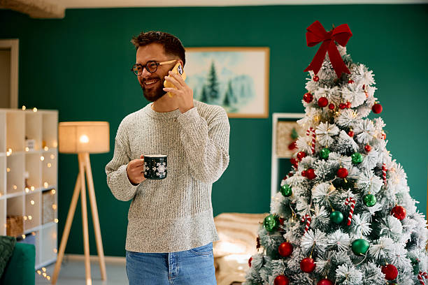 istock Young man talking on the phone and drinking coffee during Christmas holidays 2235599382