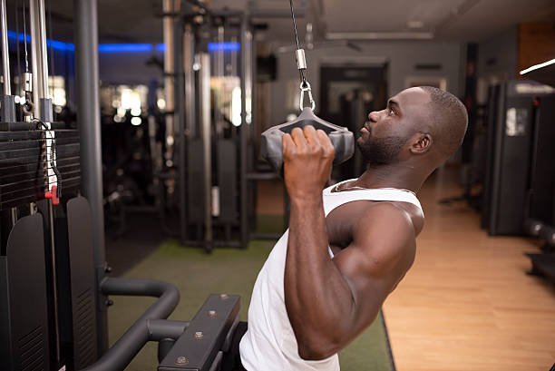 istock 30-year-old man using the pulley behind his back in the gym 2235599384