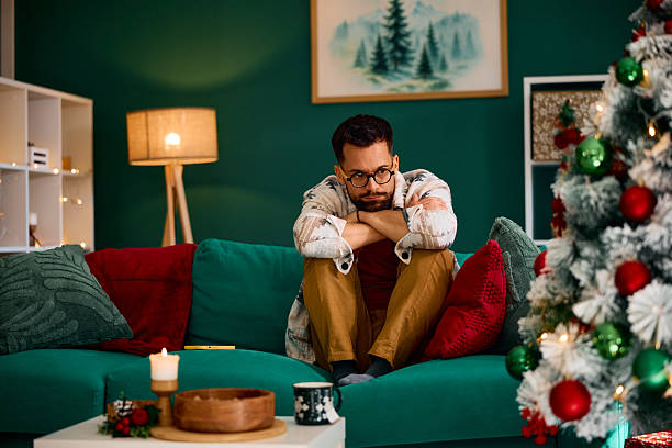 istock Sad man sitting alone on sofa during Christmas holidays 2235599492