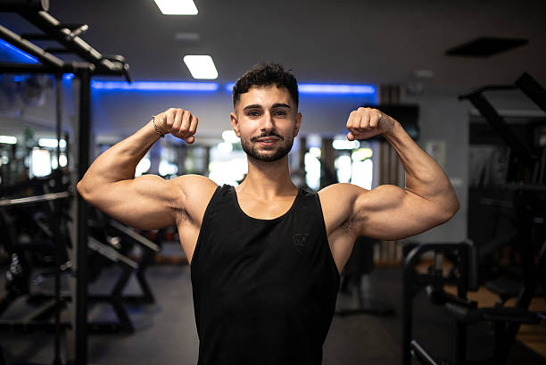 istock Arab man in his 30s does a strength pose at the gym, showing biceps and looking at camera 2235599752