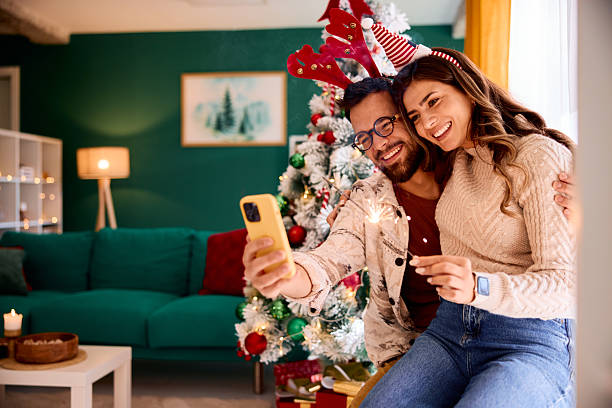 istock Happy couple taking selfie with sparklers by Christmas tree 2235599927