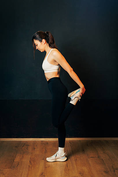 istock Fitness Model Demonstrates Standing Quad Stretch In Studio For Workout Photo 2235600558