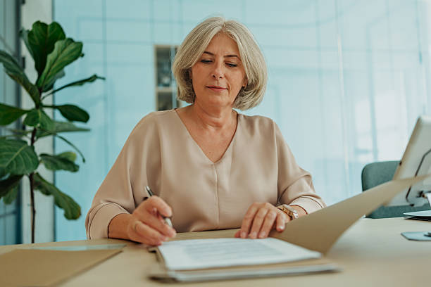 istock Professional senior woman working in a modern office, focused on her paperwork amidst an elegant corporate setting 2235609981