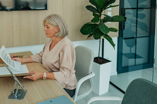 istock Senior woman reviewing documents in modern office setting with a relaxed demeanor 2235611453