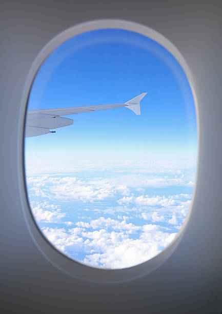 istock white Clouds and intercontinental airplane wing seen from high altitude through a window frame 2235612423