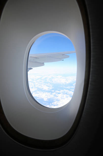 istock Clouds and intercontinental airplane wing seen from high altitude through a window frame 2235612918