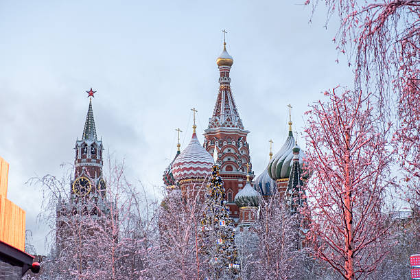 December 31, 2024, Moscow, Russia. Stunning winter landscape in Moscow showcasing iconic domes of St. Basils Cathedral and Kremlin towers surrounded by snow and bare trees.