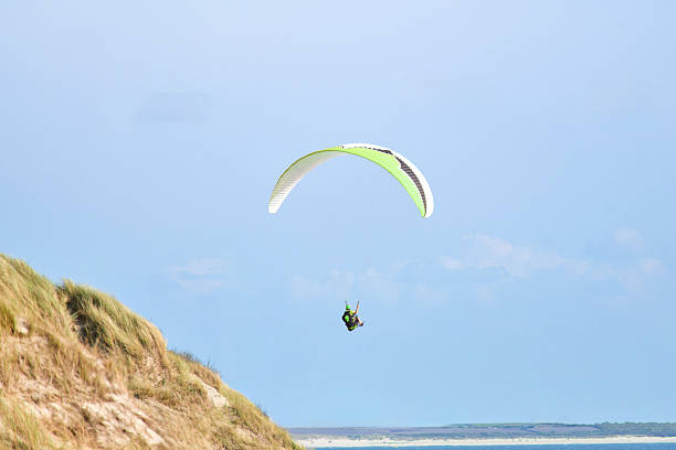 Paraglider Flying Above Beach and Dunes