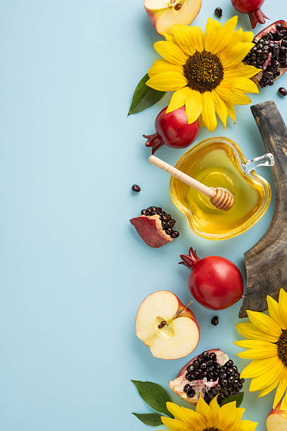 istock Flat-lay vertical arrangement featuring apples, honey with a dipper, pomegranates, and bright sunflowers, symbolizing Rosh Hashanah and Jewish New Year traditions and celebrations 2235616905