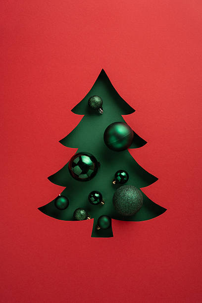 istock Creative vertical holiday card displaying a red background with a cut-out Christmas tree filled with ornaments 2235616924