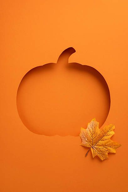 Orange vertical background featuring a pumpkin cutout with a decorative leaf symbolizing autumn and Halloween