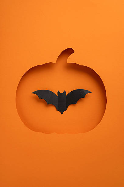 istock Creative vertical Halloween composition showing a pumpkin cutout with a bat silhouette on orange 2235616947