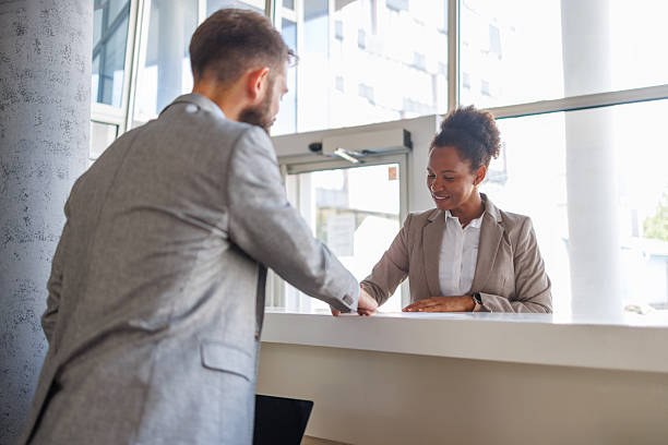 istock Businessman checking in at hotel reception desk 2235619539