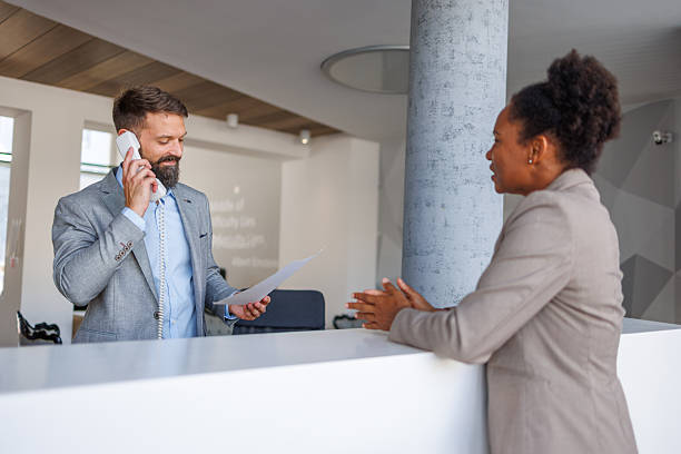 istock Businessman talking on the phone while reading a document at the reception desk 2235619540