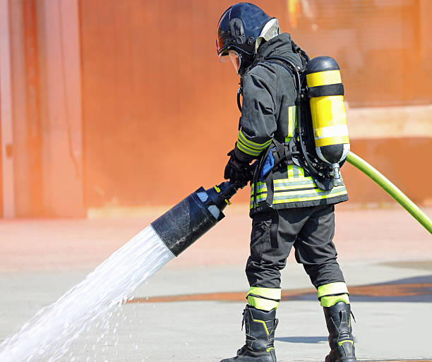 istock firefighter with a mask and oxygen tank with self-extinguishing foam during a fire emergency 2235619549