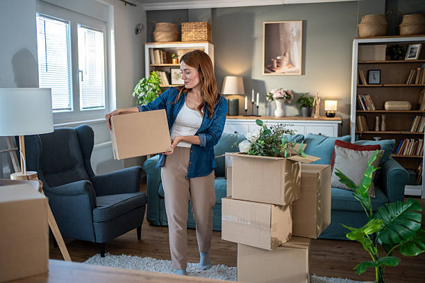 istock Woman unpacking cardboard boxes in new apartment after relocation 2235624906