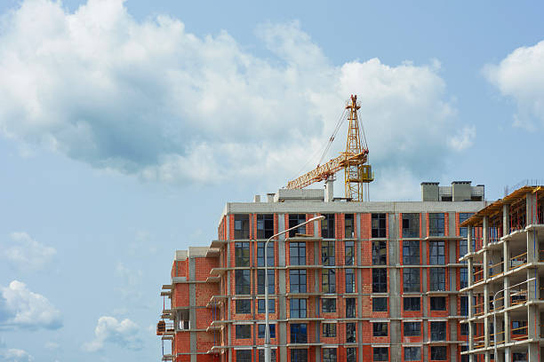 Construction site with a large tower crane at a modern building project. The unfinished building home for themes of architecture, urban development, and real estate growth.