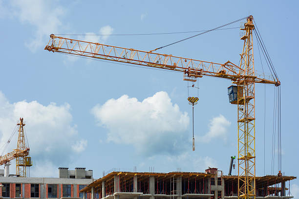 Construction site with a large tower crane at a modern building project. The unfinished building home for themes of architecture, urban development, and real estate growth.