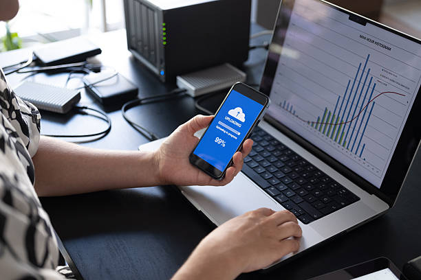 istock Woman uploading files to cloud using her smart phone 2235631036