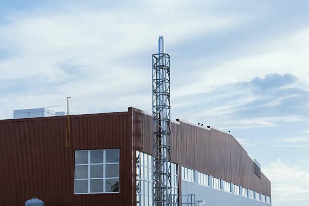 Contemporary industrial facility exterior featuring a red and white metal panel facade with silver exhaust or ventilation pipes. Concept modern industrial architecture