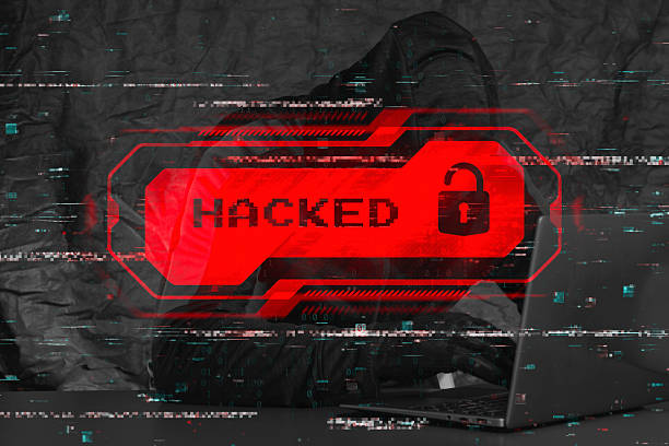 istock Hooded hacker at a laptop with a red glowing HACKED warning and a digital lock icon. Binary code overlays the scene, emphasizing the concept of data breach and cybercrime. 2235631257