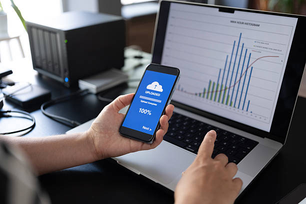 istock Woman uploading files to cloud using her smart phone 2235631722