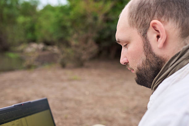 istock Hispanic man sitting outdoors, in nature, working on his laptop. 2235636597