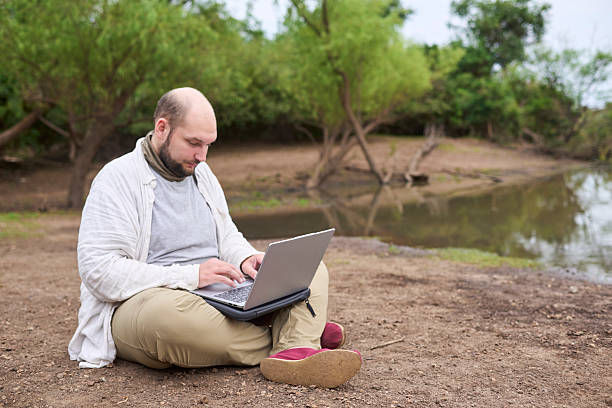 istock Hispanic man sitting outdoors, in nature, working on his laptop. 2235636742