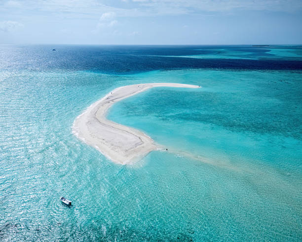 istock Aerial view capturing a pristine white sandbar surrounded by crystal-clear turquoise waters, with tourists exploring and a boat anchored nearby in the Maldives 2235638615