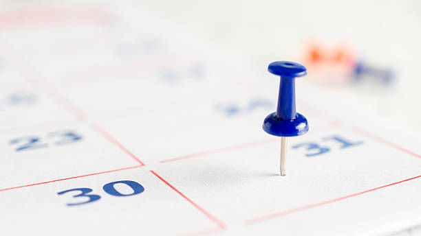 istock Blue thumbtack on a calendar page. 2235638684