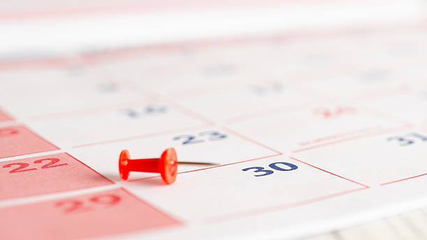 istock Red thumbtack on a calendar page. 2235638705