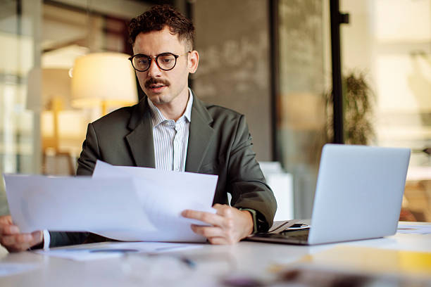istock Professional Businessman Reviewing Documents at Work in Modern Office 2235638911