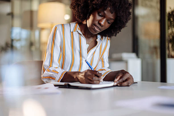 istock Focused Professional Woman Writing Notes at a Modern Office Environment 2235638940