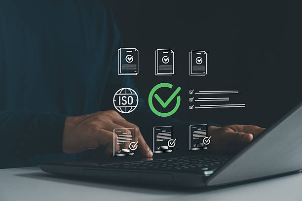 istock Businessman working on laptop with document icons, ISO symbol, and check marks, representing business quality control, certification standards, compliance management and regulatory approval process. 2235641112