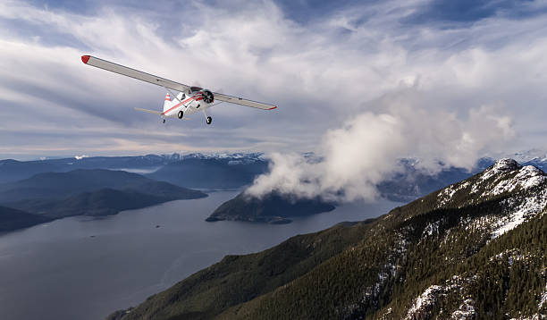 istock Small Airplane Flying Over Mountain Range Under Blue Skies and White Clouds 2235643958