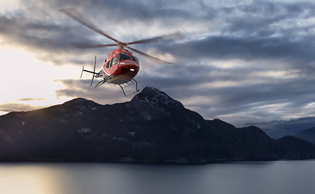 istock Red Helicopter Flying Over Scenic Mountains and Lake at Sunset 2235644258