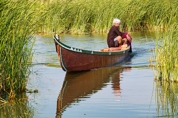 A man moves with traditional mashoof in the Mesopotamian Marshes near Chibayish, Iraq, on a sunny day.