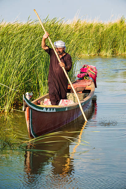 A man moves with traditional mashoof in the Mesopotamian Marshes near Chibayish, Iraq, on a sunny day.