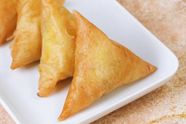 Close-up detail of golden fried samosa, traditional savory pastry filled with spiced vegetables.